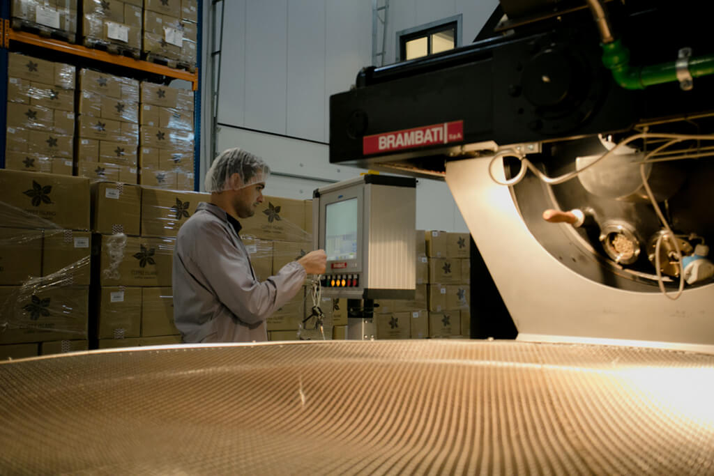 A coffee professional touches the artisan roasting machine