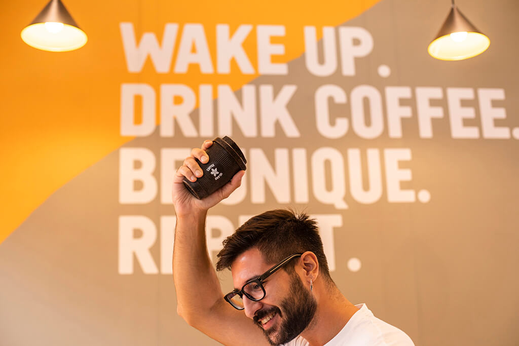 A man holding a reusable cup in a coffee island store