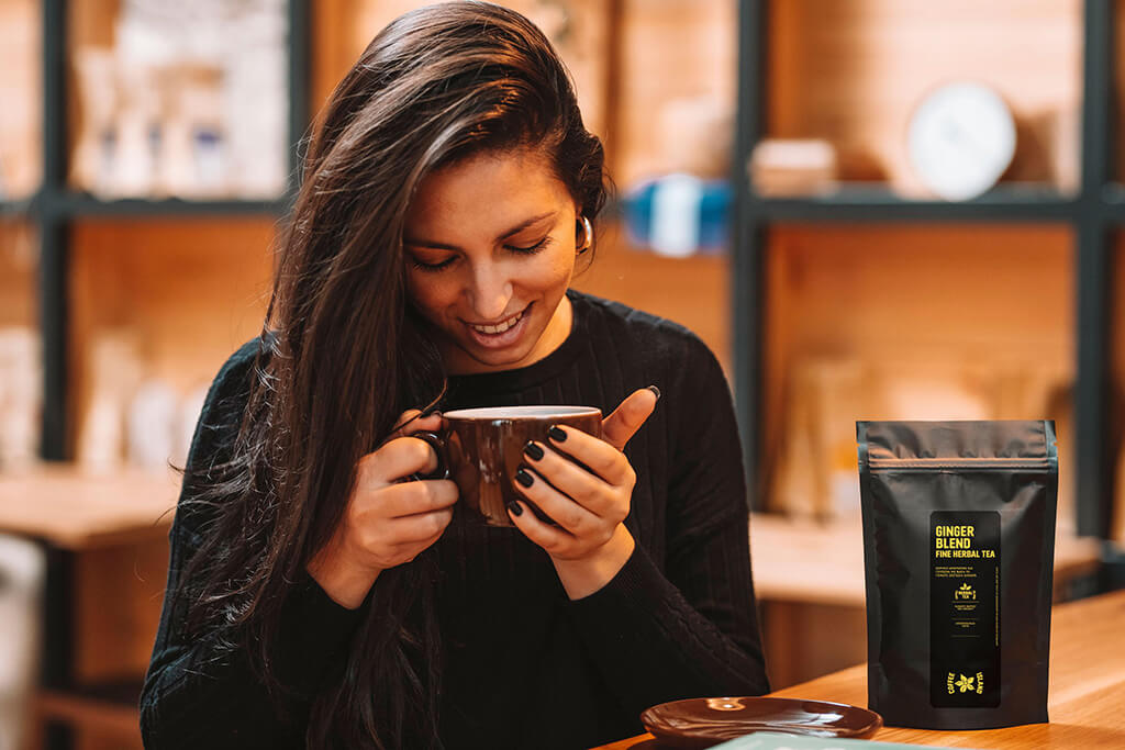 A woman enjoying her ginger blend tea from Coffee Island