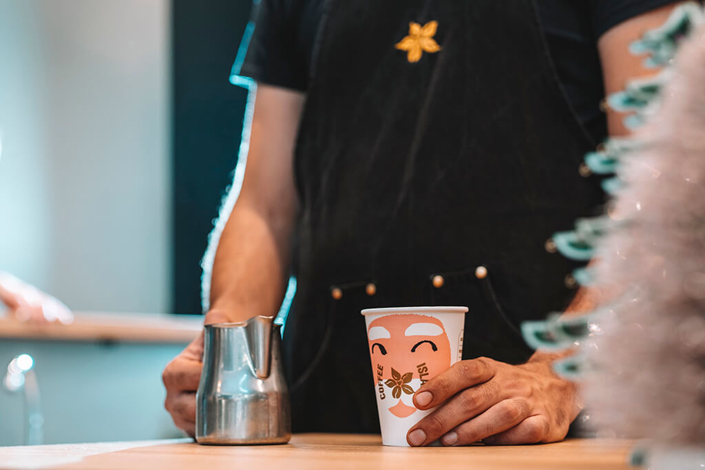 Coffee Island barista holding Santa Christmas cup and milk