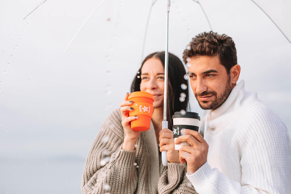 A man and a woman holding Coffee Island's reusable cups with tea