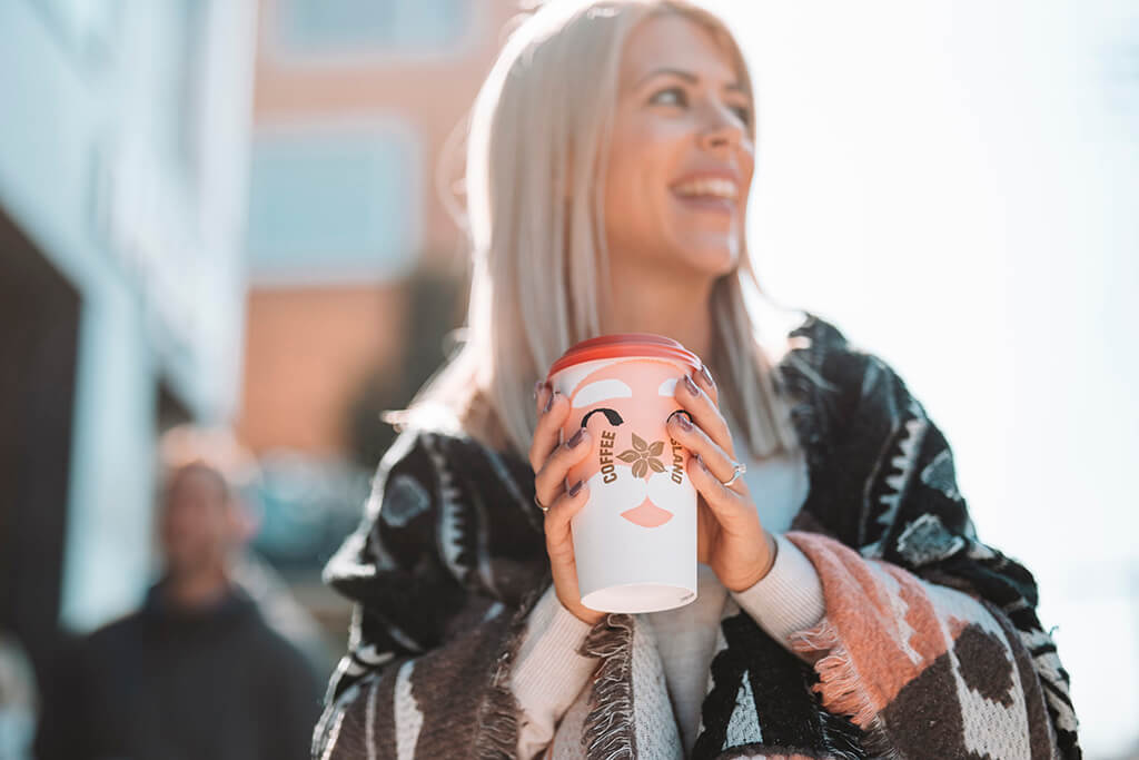 Woman happily holding her Coffee Island Santa Christmas Cup