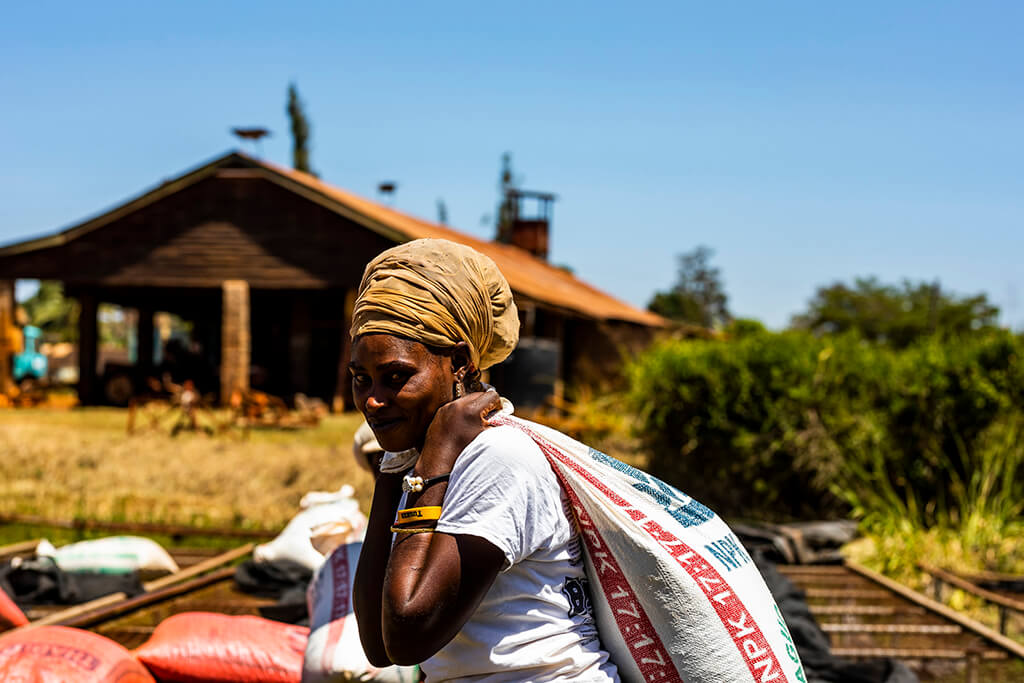 Coffee Island International Women's Day, a woman carrying a sack of coffee beans.