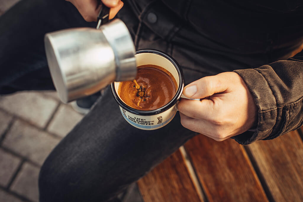 A man pouring coffee in a mug.