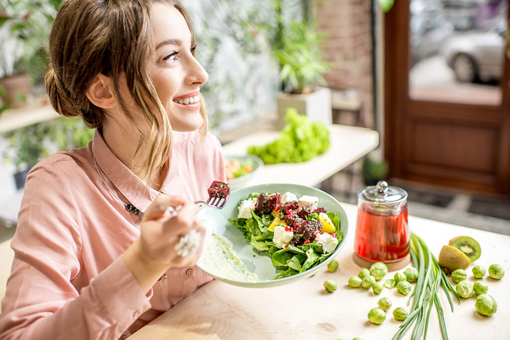 A woman eating and enjoying a vegetarian salad.