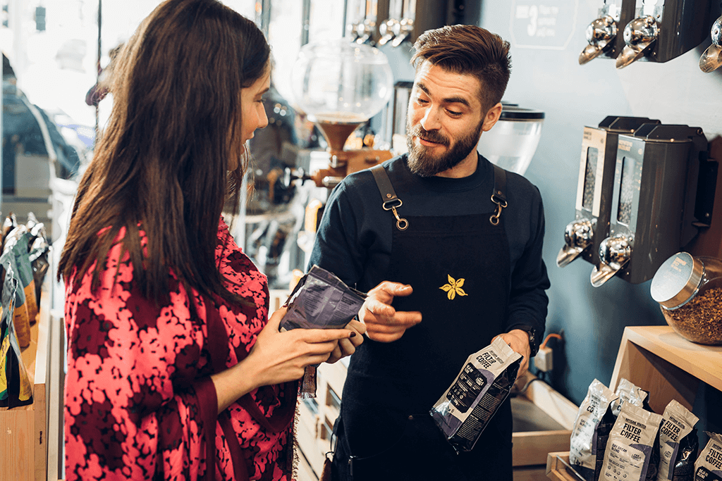 A Coffee Island's staff showing different filter coffee packages to a customer.