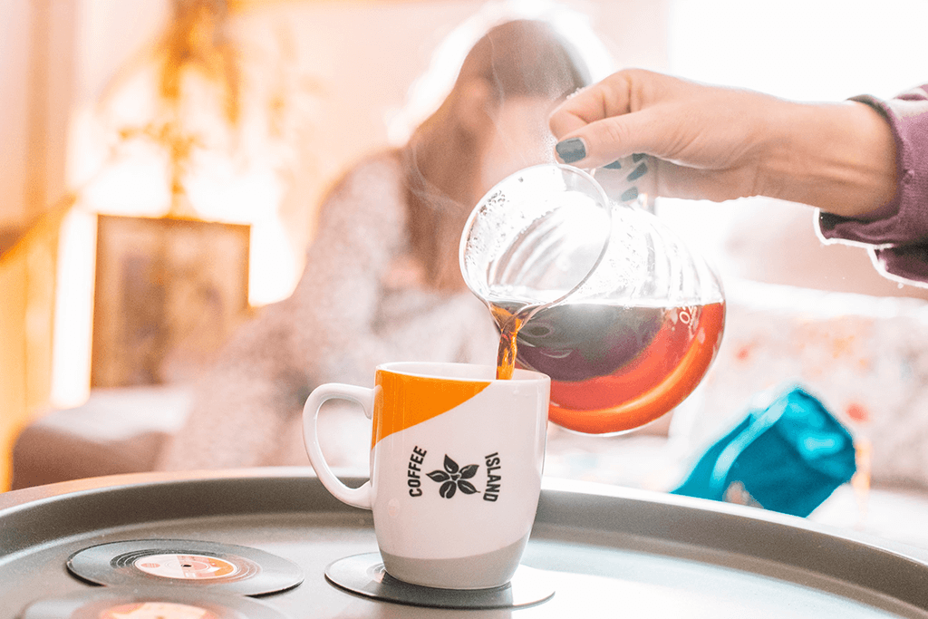 A woman pouring filter coffee in a Coffee Island mug.