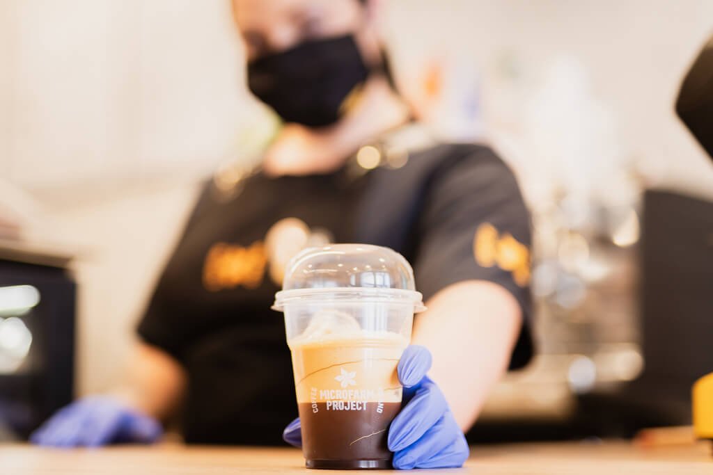 Coffee Island's barista holding an ethiopia adola cup