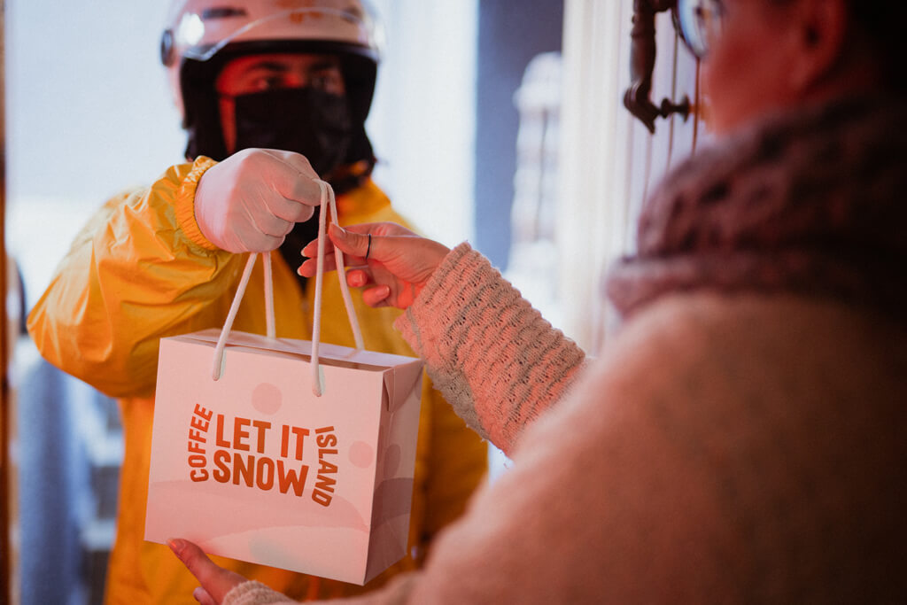 Delivery boy holding Coffee Island's Christmas bag.