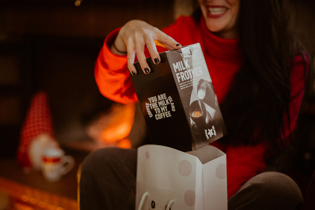 A woman unboxing Coffee Island's Milk Frother. 