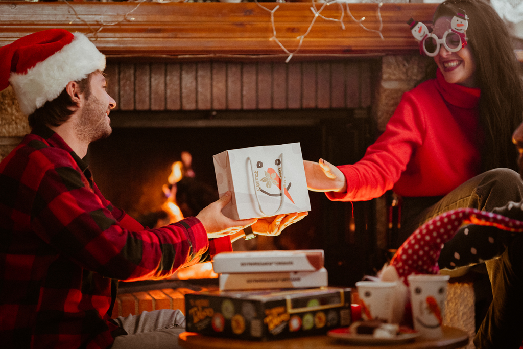 A man offering a Coffee Island's Christmas gift to a woman. 