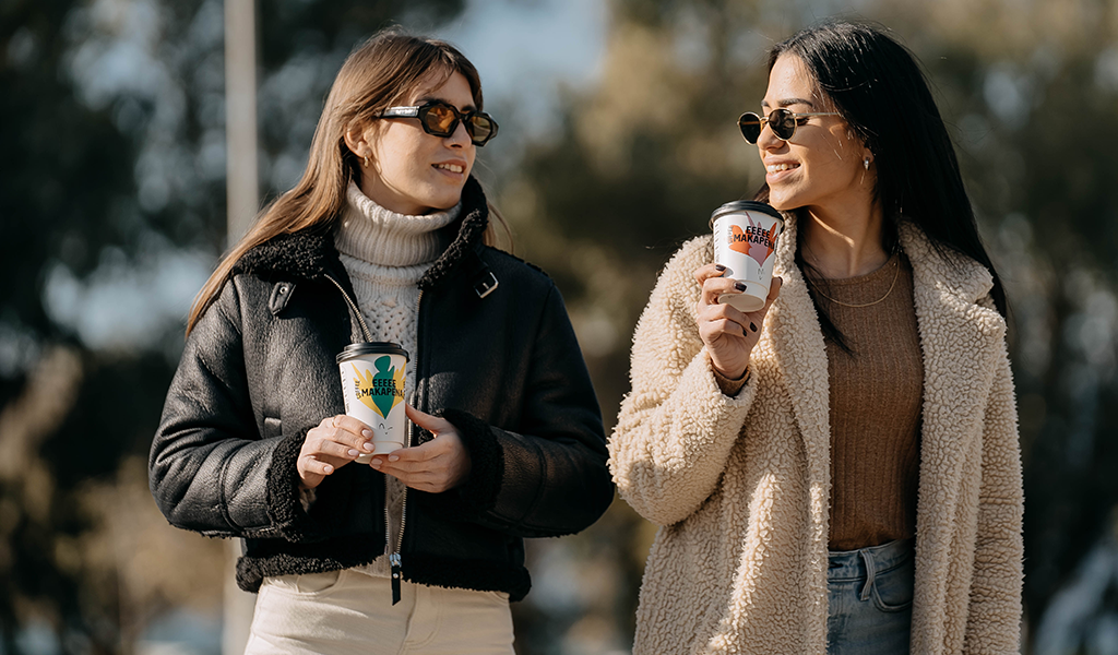 girls smiling with coffee island coffee cup in their hand