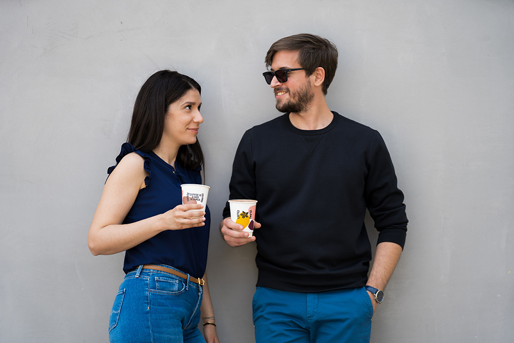 Δύο άτομα κρατάνε ποτήρι Coffee Island χαμογελώντας